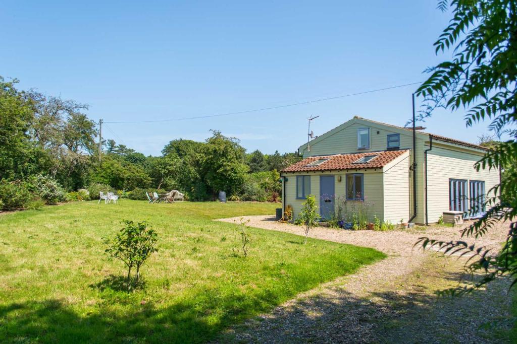 una casa en un campo al lado de un patio en Hen Barn, en West Beckham