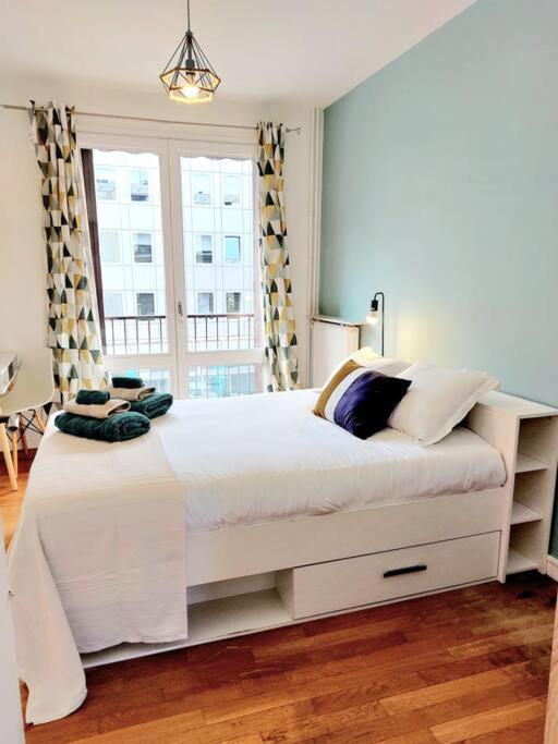 a bedroom with a large white bed with a window at Lumineux T5 en centre ville in Angoulême