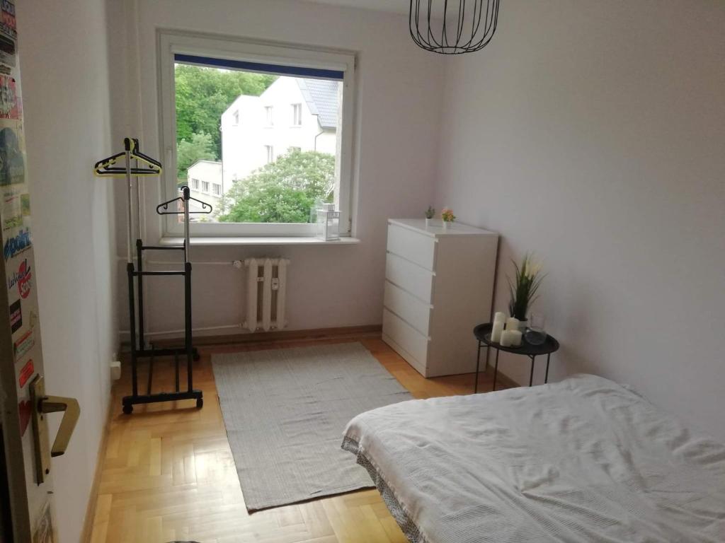 a white bedroom with a bed and a window at Apartament Józio in Gdańsk