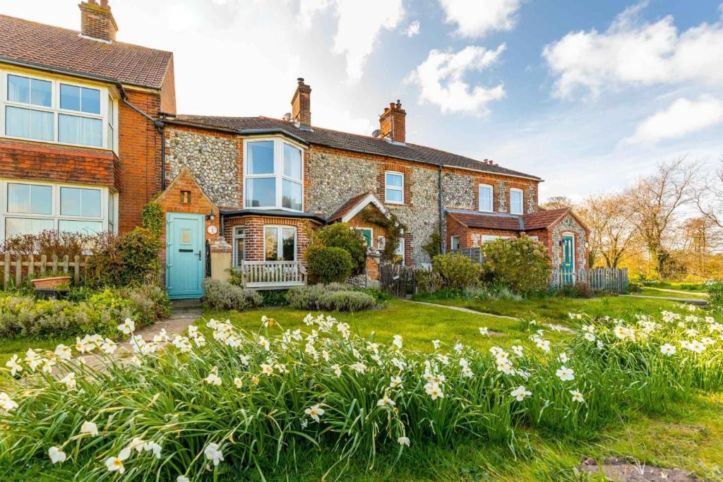 una casa de ladrillo con un patio con flores en St Josephs Cottage, en West Runton