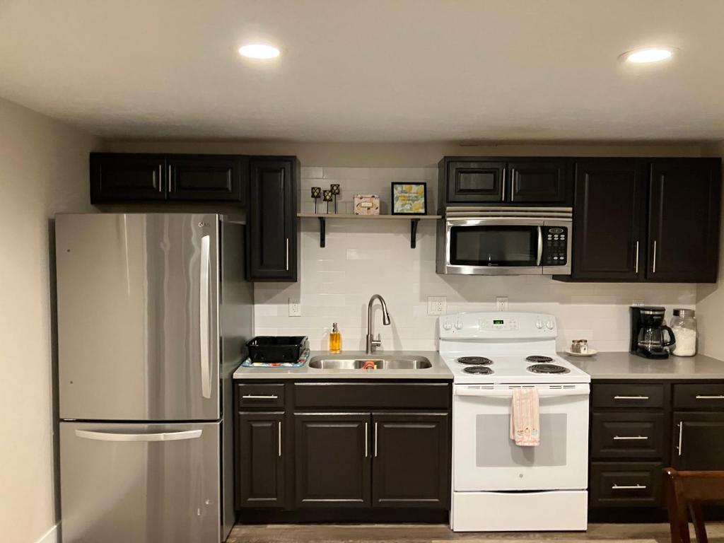 a kitchen with black cabinets and a white refrigerator at Cozy Getaway near SLC Airport & Downtown - 1st floor Apartment in Salt Lake City