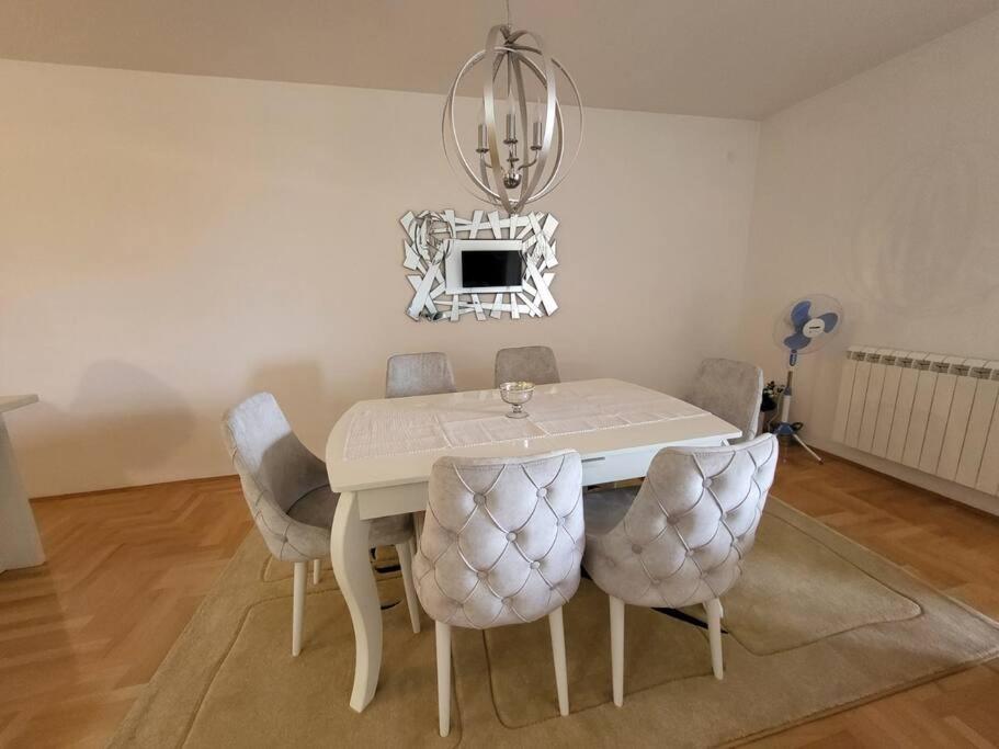 una mesa de comedor blanca con sillas y una lámpara de araña en Luxury Central Apartment, en Strumica