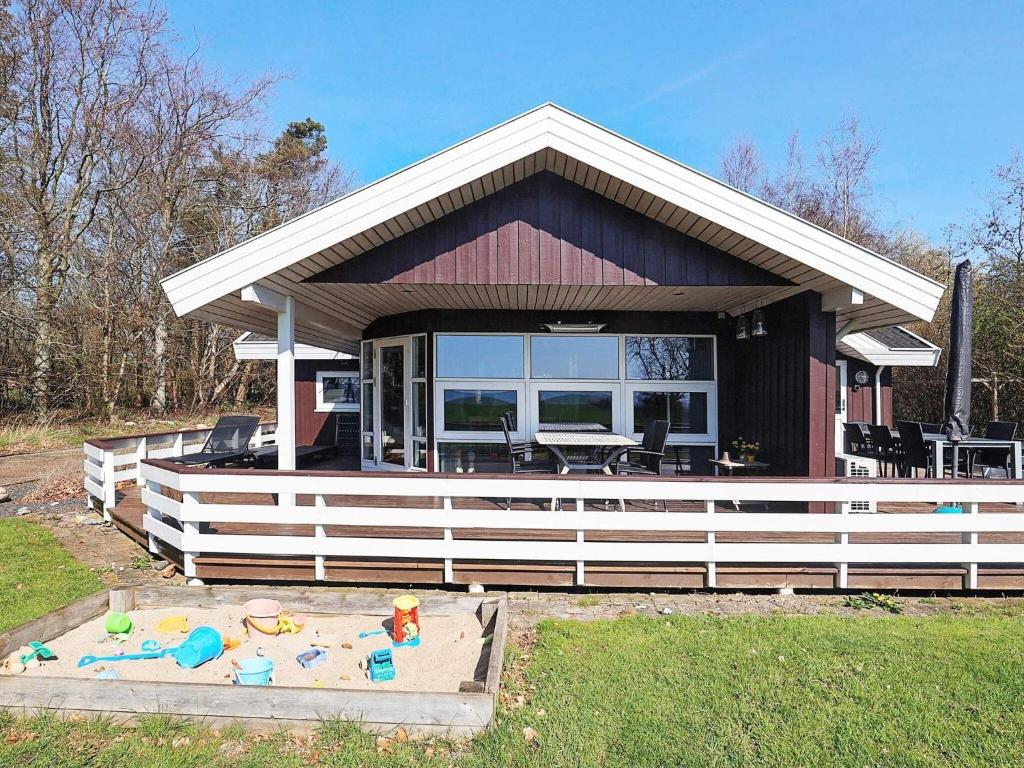 SillerslevにあるThree-Bedroom Holiday home in Øster Assels 1のデッキ(テーブル、椅子付)が備わる家