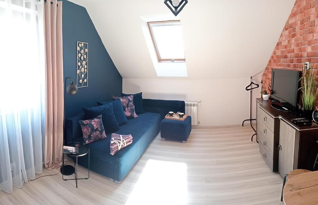 uma sala de estar com um sofá azul e uma televisão em Apartament na Glinkach 22 em Augustów