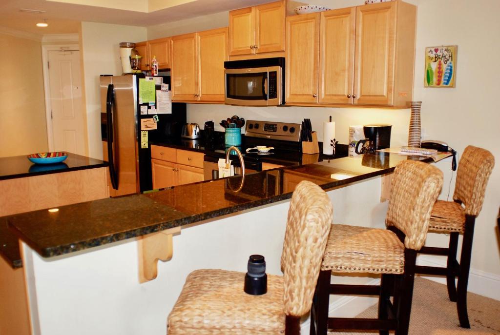 a kitchen with a counter with chairs and a refrigerator at Holiday Isle 107 in Dauphin Island