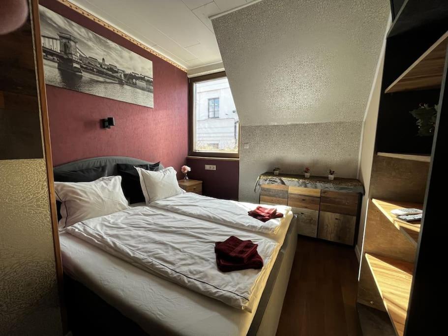 um quarto com uma cama grande e uma parede vermelha em Rose cosy, tiny studio with shared rooftop terrace and jacuzzi em Budapeste
