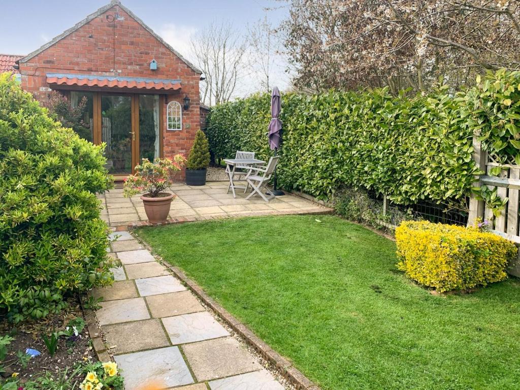 a garden with a patio with a table and chairs at Cloverleaf in Saltfleetby Saint Clement