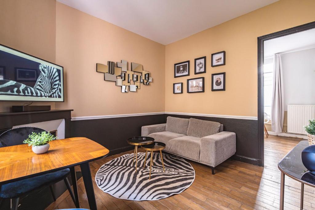 a living room with a couch and a table at MM Suites Reims Centre Terasse in Reims