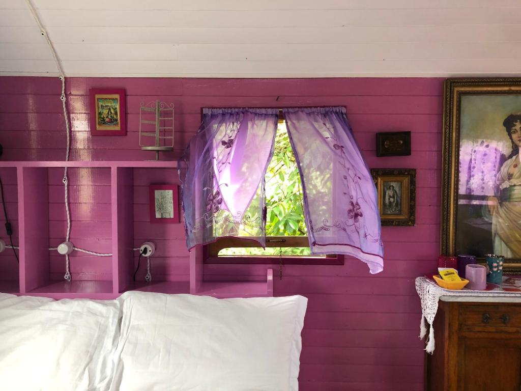 a pink bedroom with a window and a purple wall at Azienda agricola Della Mezzaluna in Stiava