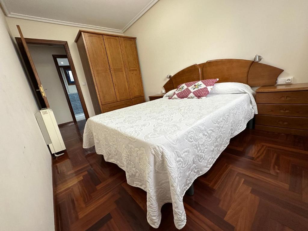 sypialnia z białym łóżkiem z drewnianym zagłówkiem w obiekcie Apartamento Salgueirón w mieście Cangas de Morrazo