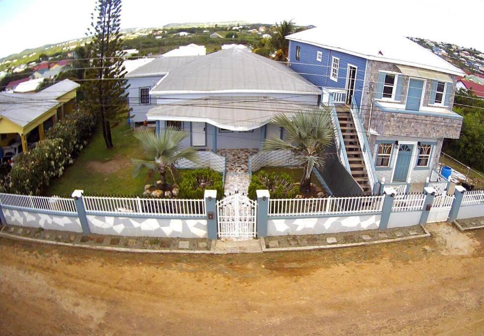 a large blue house with a white fence at Adama Suites in Potters Village