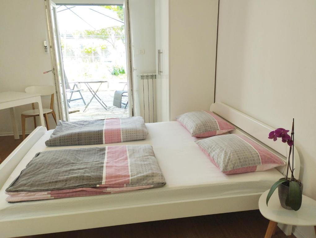 1 cama blanca con 2 almohadas y ventana en Active Apartments Koper, en Koper