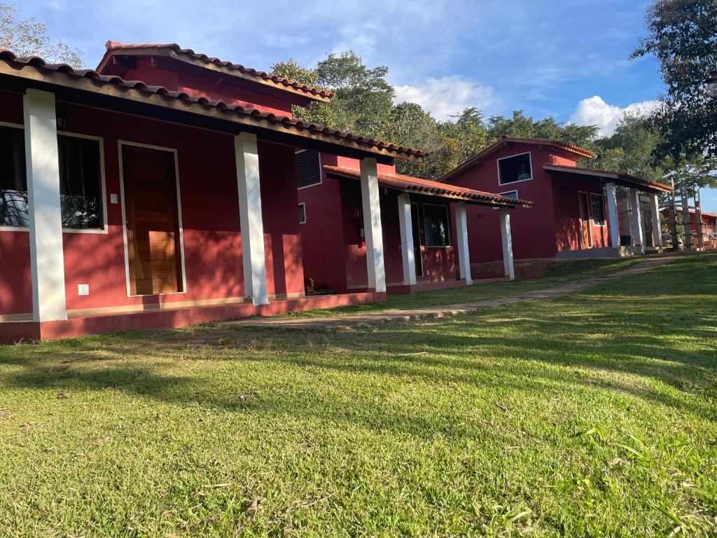 una casa roja con un patio de hierba delante de ella en Chalés do Recanto, en São João del Rei