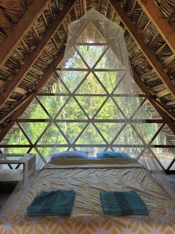 a bed in a tent with two pillows on it at Pachamaya River Hostel in Lanquín