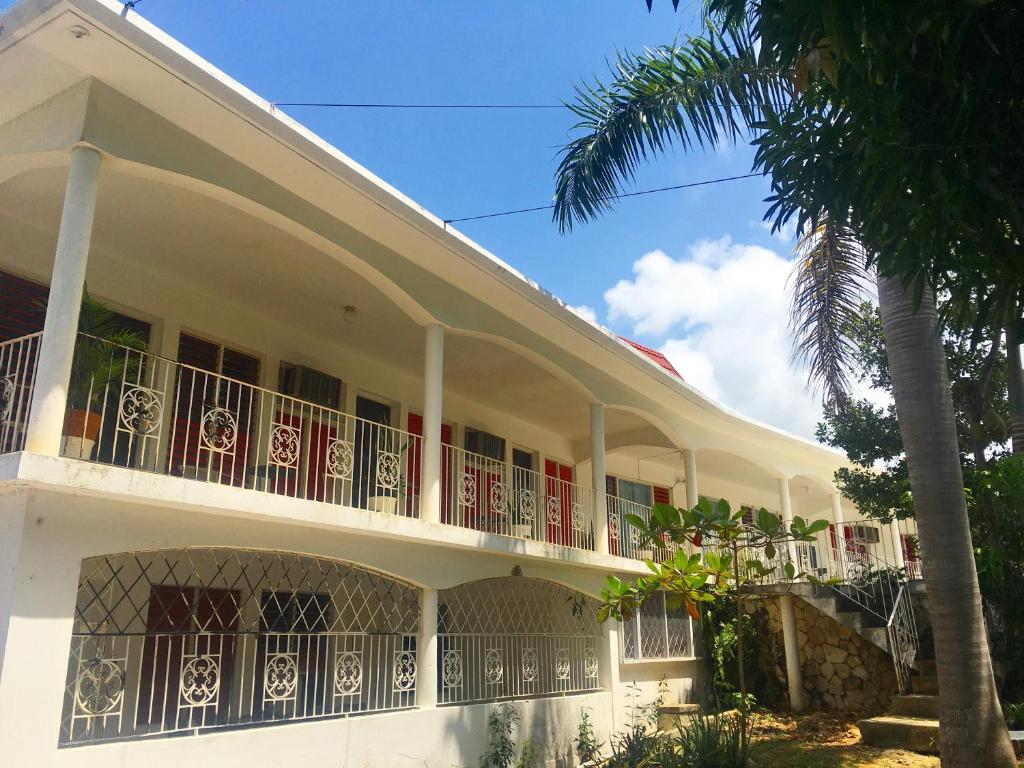 a white building with a balcony and a palm tree at African Symbol Guest House in Montego Bay