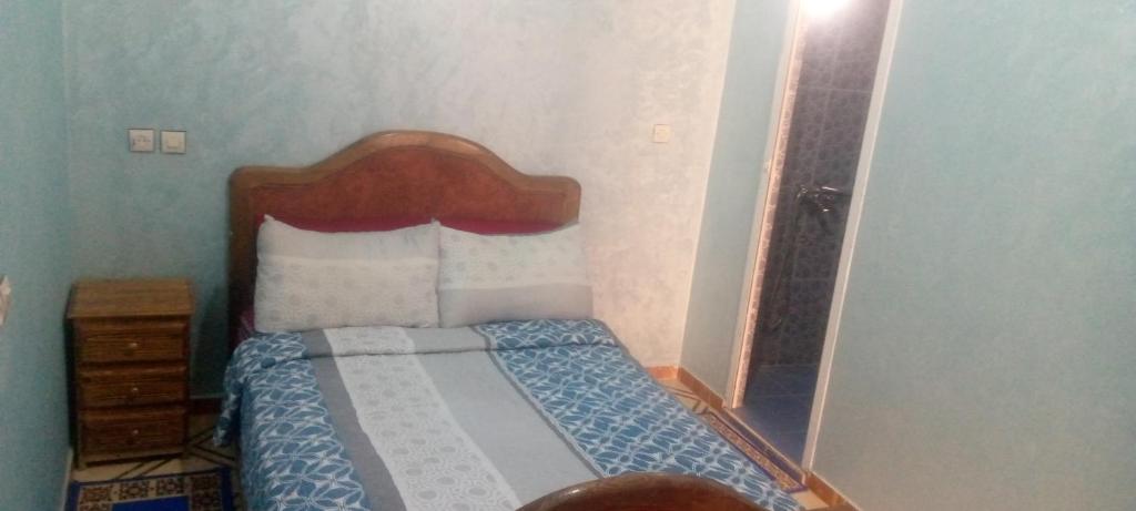 um pequeno quarto com uma cama e uma cabeceira em madeira em شقة العتماني للكراء اليومي em Rissani