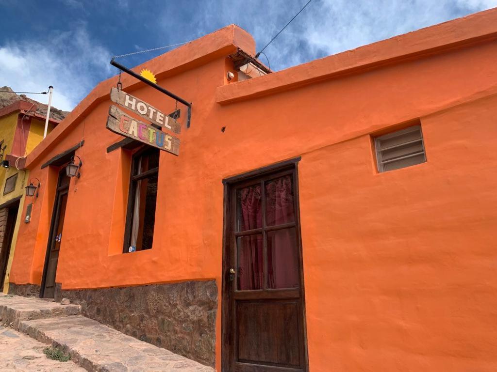 un bâtiment orange avec un panneau au-dessus d'une porte dans l'établissement Hotel Cactus Cerro, à Purmamarca