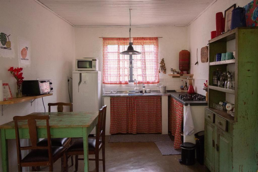 Casa Morango Gonçalves في جونسالفيس: مطبخ مع طاولة وثلاجة