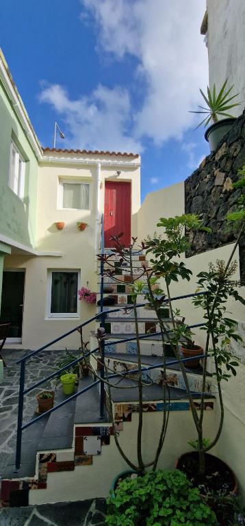 a house with a red door and stairs with plants at A-Típica GuestHouse in Ponta Delgada