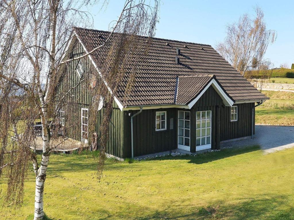 Hjarbækにある8 person holiday home in L gstrupの木の前の小さな緑の家