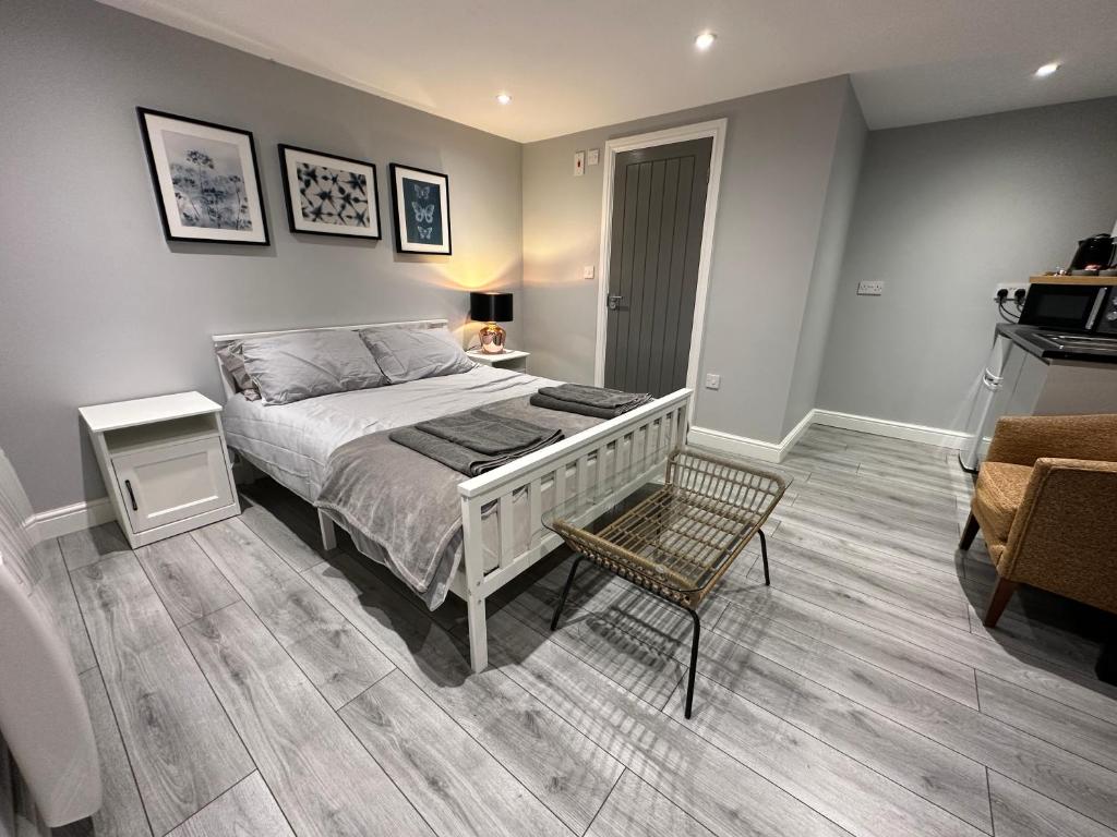 a bedroom with a bed and a table and a chair at Luxury Detached Studio Apartment - Free Super Fast WiFi - Free Parking - 15 Mins from Luton Airport in Luton