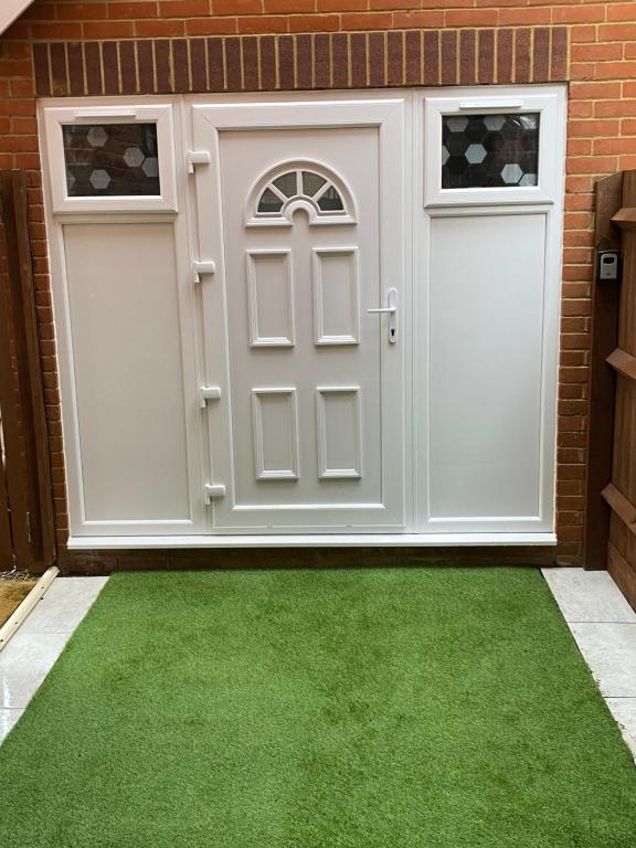 a garage with two doors and green grass at Guest House in Milton Keynes in Milton Keynes