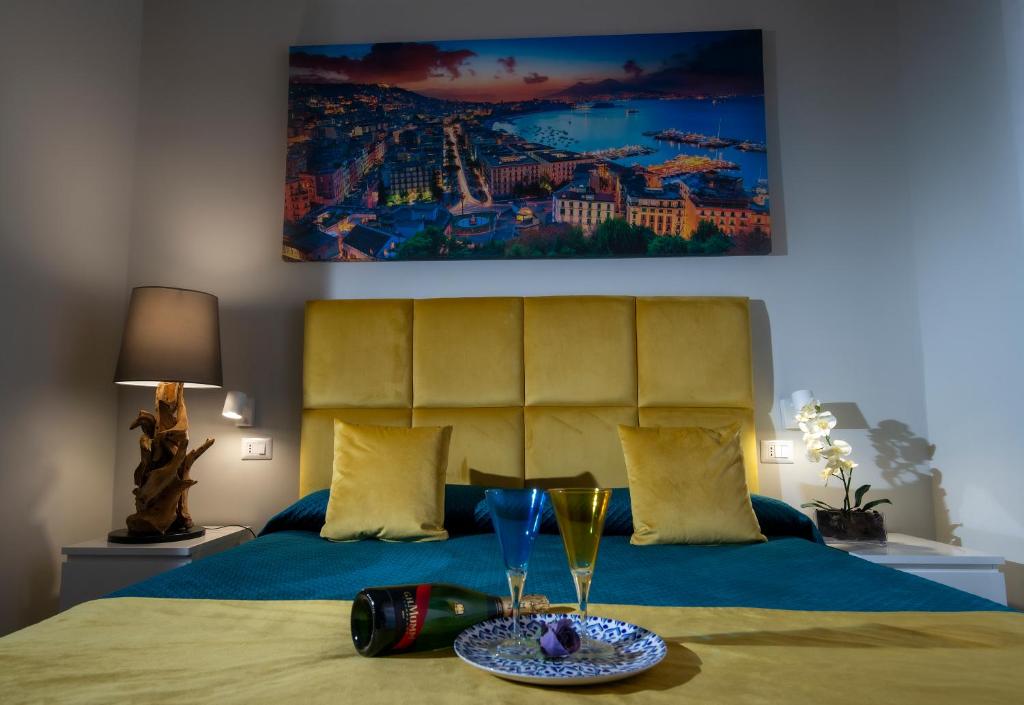 Un dormitorio con una cama con una botella y vasos. en VIVI A NAPOLI en Nápoles