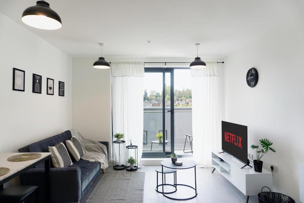 a living room with a couch and a tv at The Madison Apartment by TTLG Stays in Hemel Hempstead
