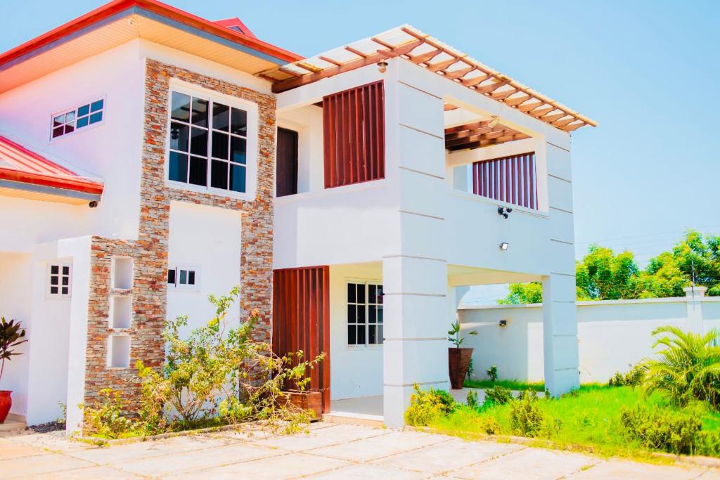 a white house with a red door at Lovely 4 Bedroom House with Solar Power Security Cameras WiFi and Pergola near Devtraco Court Community 25 Tema in Tema