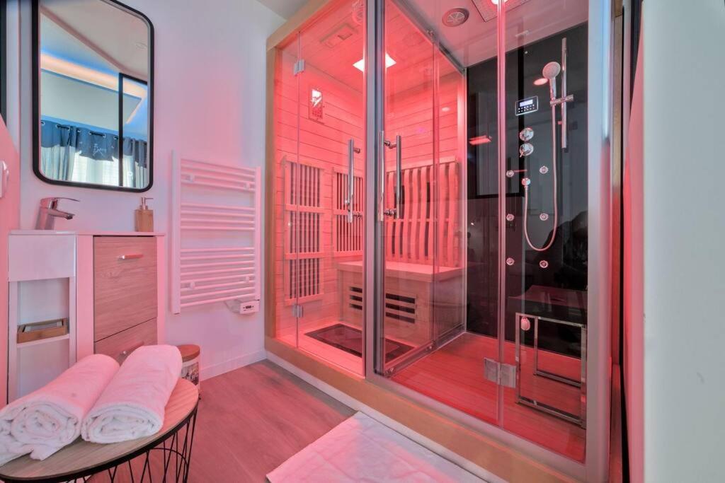 uma casa de banho com chuveiro e um banco em frente a uma porta de vidro em Spa Des lumières Sauna/Hammam em Montigny-lès-Metz