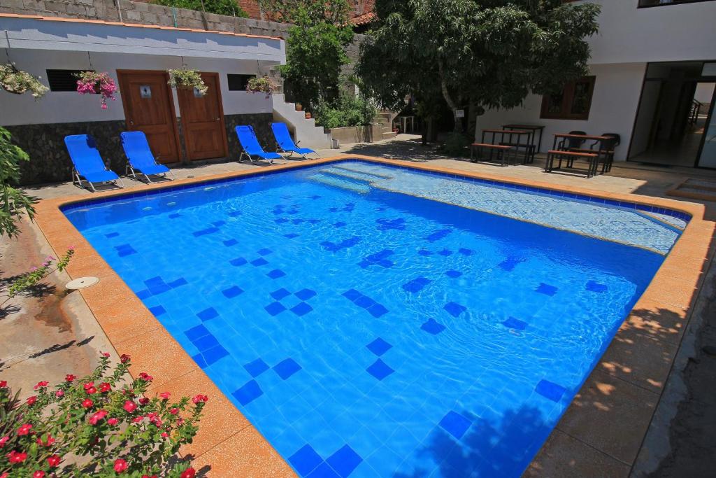 una gran piscina azul con sillas azules en un patio en Apartahotel La Villa Santa fe de Antioquia, en Santa Fe de Antioquia