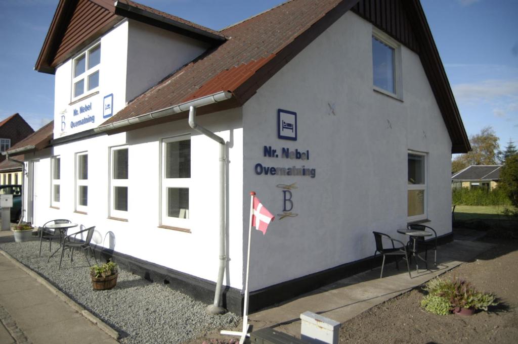 a white building with tables and chairs in front of it at Nr. Nebel Overnatning Hostel in Nørre Nebel