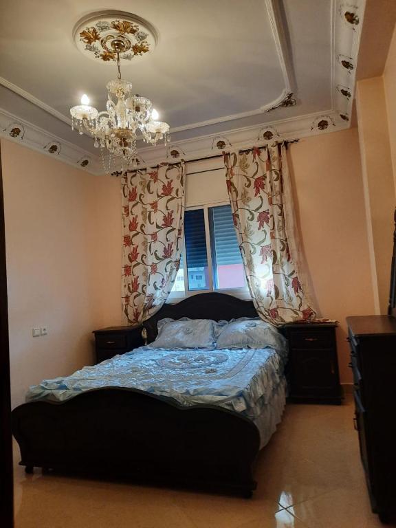 una camera da letto con un letto con un lampadario a braccio e tende di JERDOUH For FAMILY ONLY a Tétouan