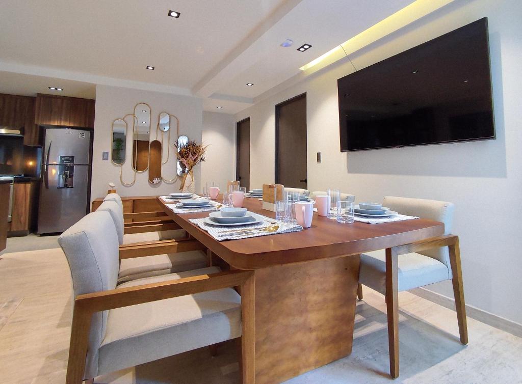 a dining room table with chairs and a television on a wall at Nowness in Mexico City