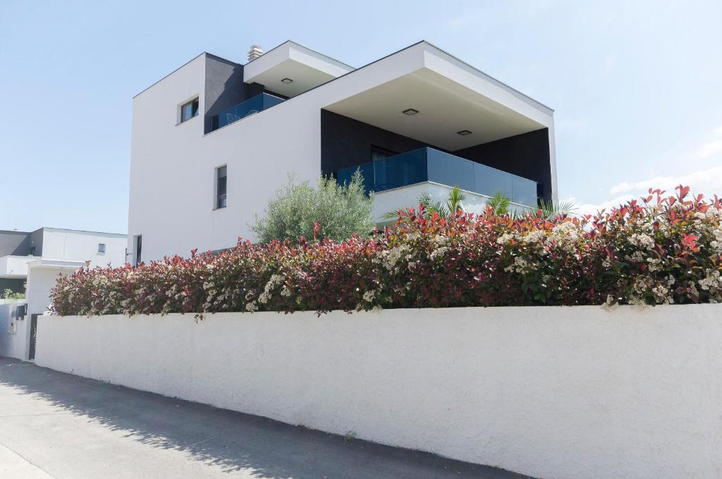 a white building with flowers in front of it at Apartments Ella in Vodice