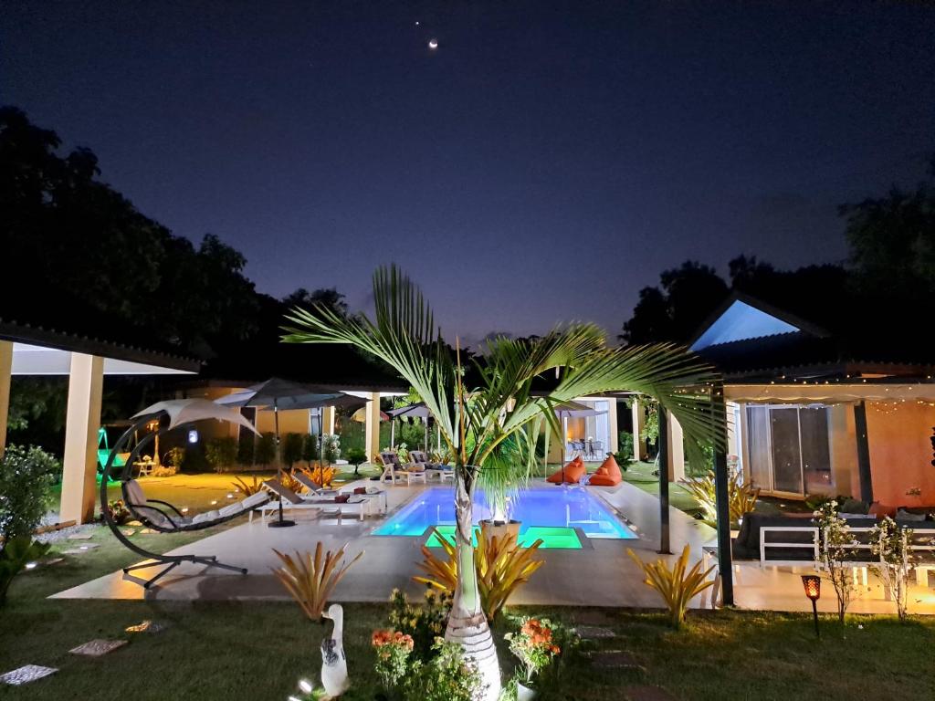 a pool with a palm tree in a yard at night at Pool Villa, Resort, Mae Ramphueng Beach, Ban Phe, Rayong, Residence M Thailand in Ban Chamrung