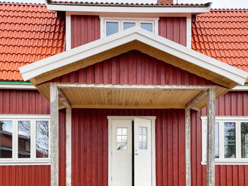 una casa roja con techo rojo y puerta blanca en Holiday home VÄSTRA ÄMTERVIK, en Östra Ämtervik