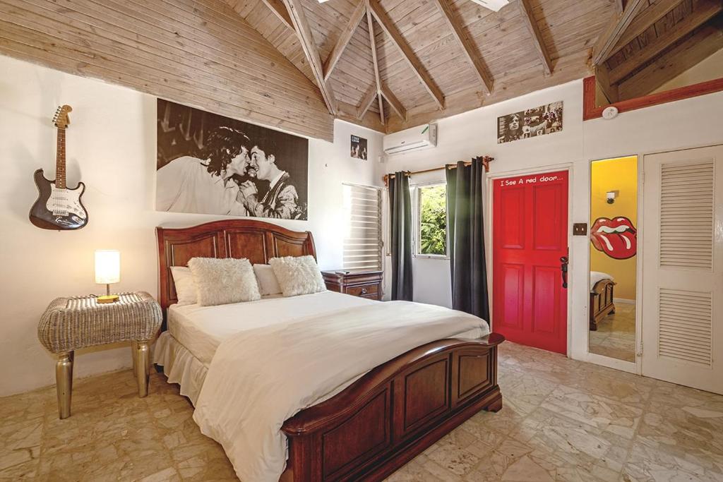 a bedroom with a large bed and a red door at Hospitality Expert Jagger - Tour Pool Bar Beach in Montego Bay