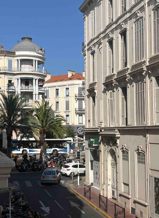 une rue de ville avec des bâtiments, des voitures et un bus dans l'établissement Résidence Raphaël Croisette, à Cannes