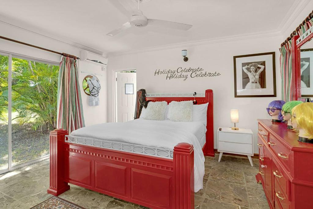 a bedroom with a red bed and a window at Hospitality Expert Madonna Tour Pool Bar Beach in Montego Bay