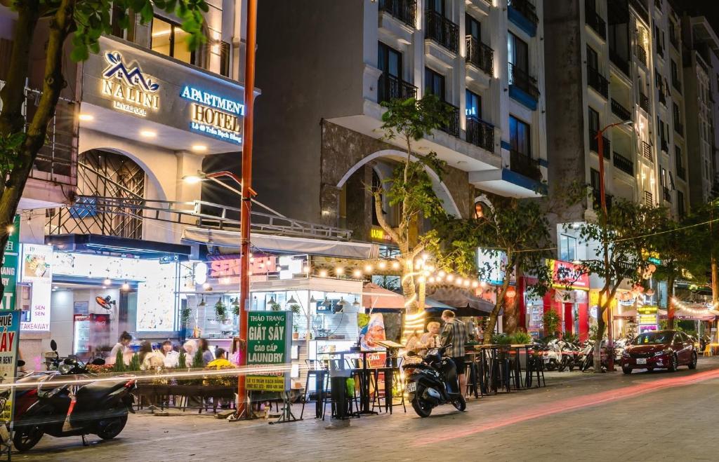 a city street at night with people sitting at tables at NALINI Hotel & Apartment in Da Nang