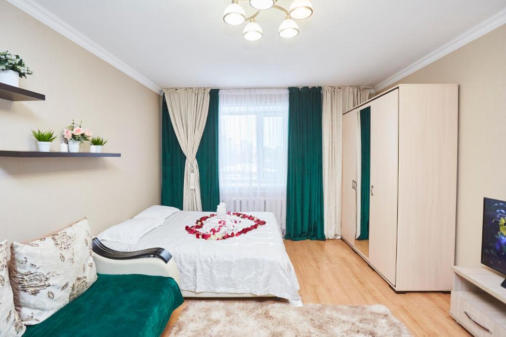a bedroom with a bed and a green couch at Просторная 1ком квартира у Набережной Астаны in Astana