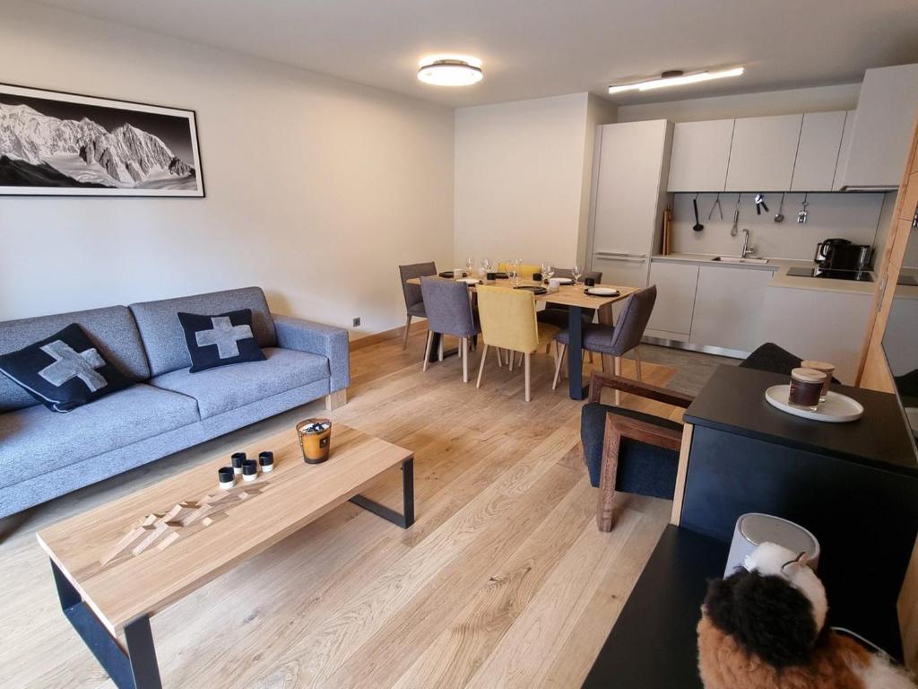 un salon avec un canapé bleu et une table dans l'établissement Appartement 6 pers avec terrasse au cœur du village, résidence neuve avec sauna et parking - FR-1-598-141, aux Gets