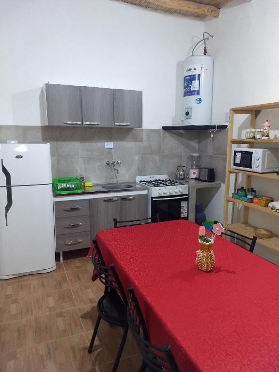 cocina con mesa y mantel rojo en Cabaña La Angostura en Fiambala
