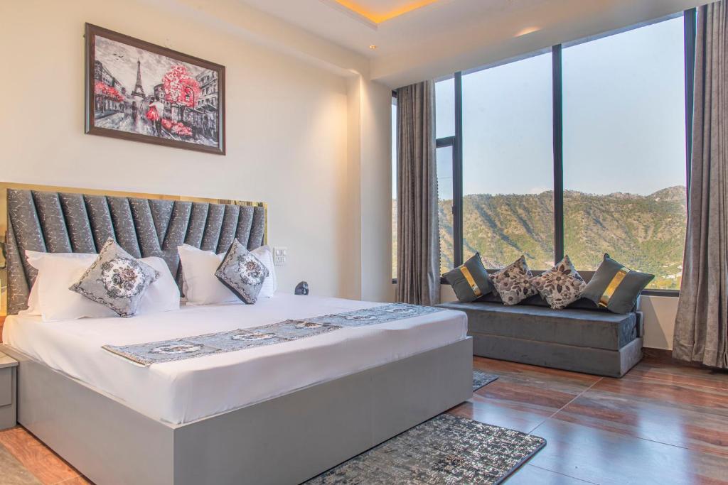 ein Schlafzimmer mit einem großen Bett, einem Sofa und Fenstern in der Unterkunft Mystic Hill Crest Luxurious 2 BHK Apartments in Kasauli
