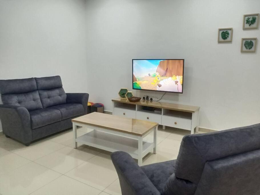 uma sala de estar com dois sofás e uma televisão em Sakura homestay 5 bedrooms - Spring Lopeng 14 pax em Miri