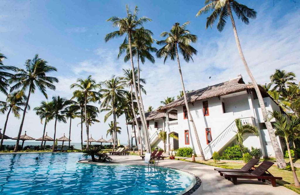a resort with a swimming pool and palm trees at Muine Sun & Sea Resort in Mui Ne