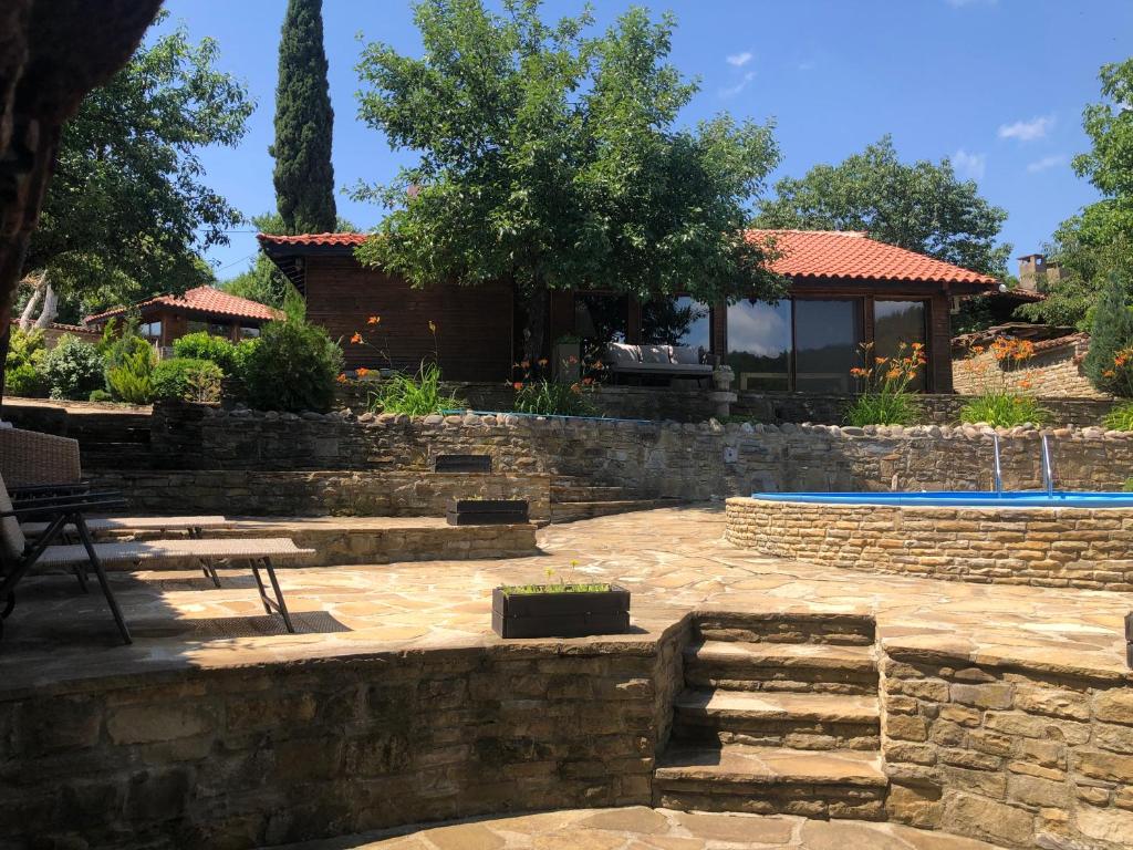 a backyard with a stone wall and a swimming pool at Попската къща-възрожденски дух и съвременни удобства in Medven