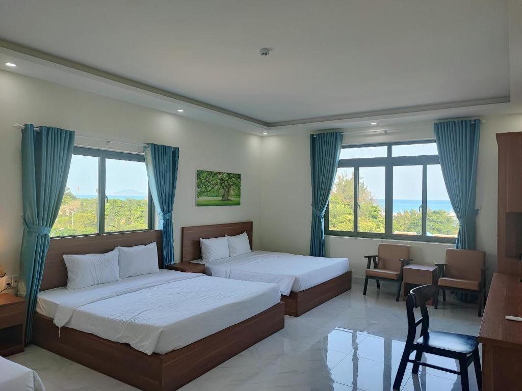 a bedroom with two beds and a table and chairs at Hoàng Anh Côn Đảo Hotel in Con Dao