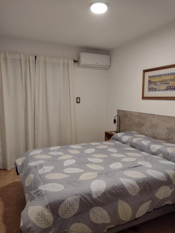 a bedroom with a bed with a blue and white blanket at Departamento amoblado Rio Cuarto in Río Cuarto